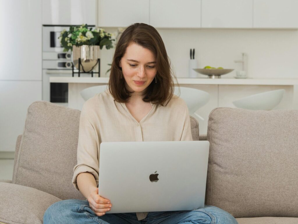 pexels-photo-4680242-4680242 Young woman comfortably using a laptop on her sofa in a bright living room.